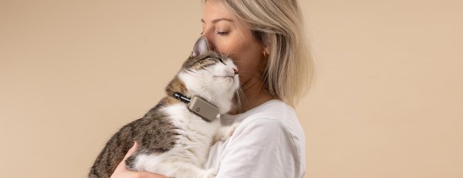 A woman hugging a cat that's wearing a Tractive GPS tracker